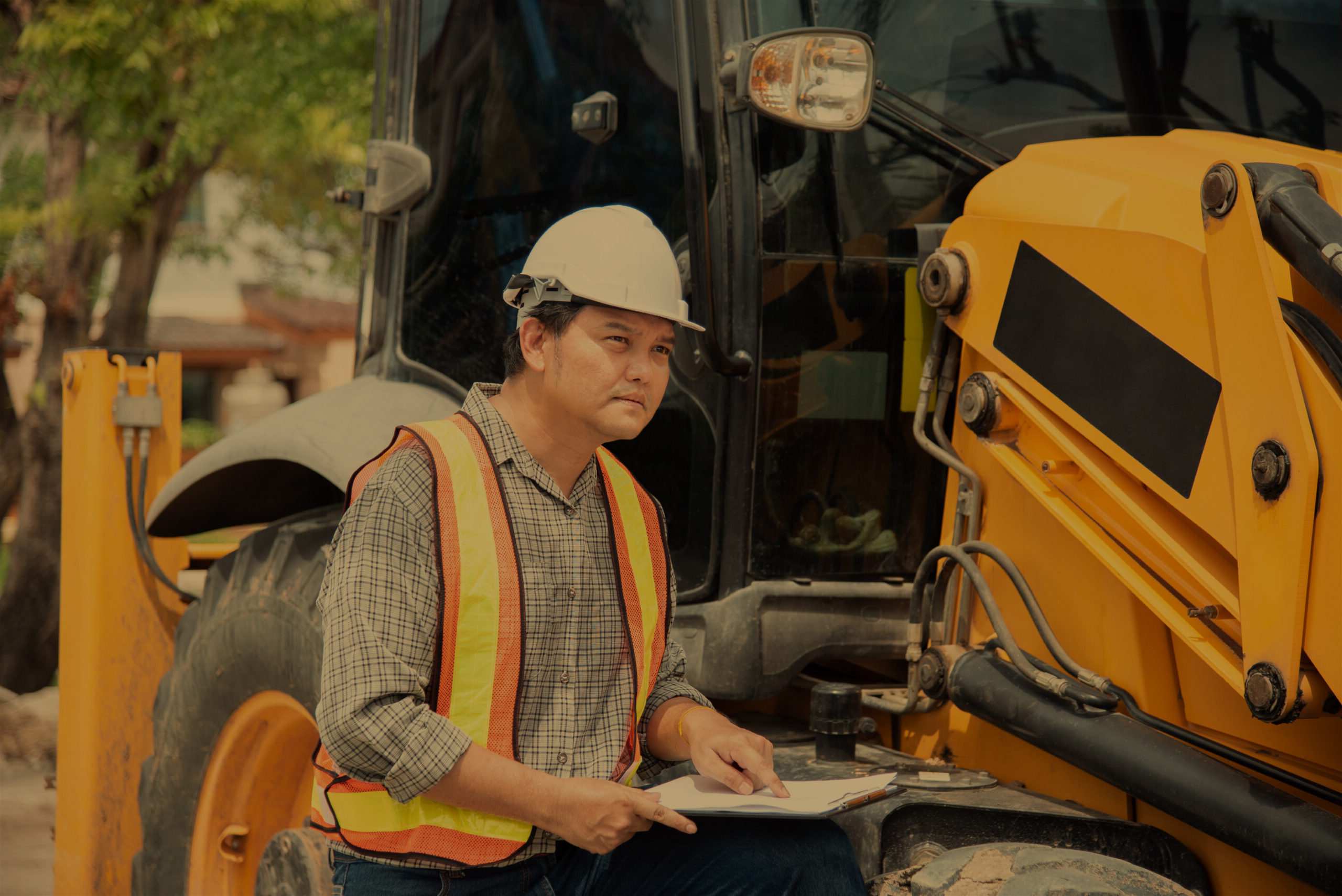 Asian man civil construction engineer worker or architect with helmet and safety vest working and holding a paper board note for see blueprints or plan at a building or construction site